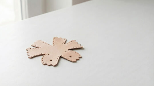 A flat leather DIY kit piece resting on a white table in soft morning light, before stitching begins.