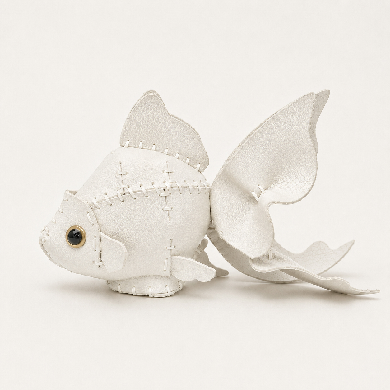 The White colourway — a goldfish model in white leather, hand-stitched, with fanned fins and a gold-ringed eye.