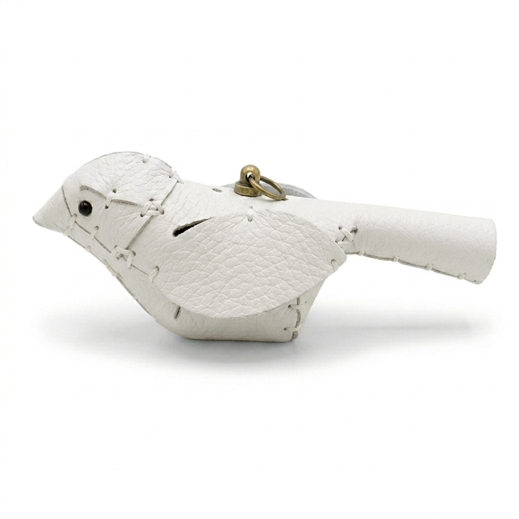 The White colourway — a single leather bird, side view, pebble-grain panels whip-stitched with pale thread.
