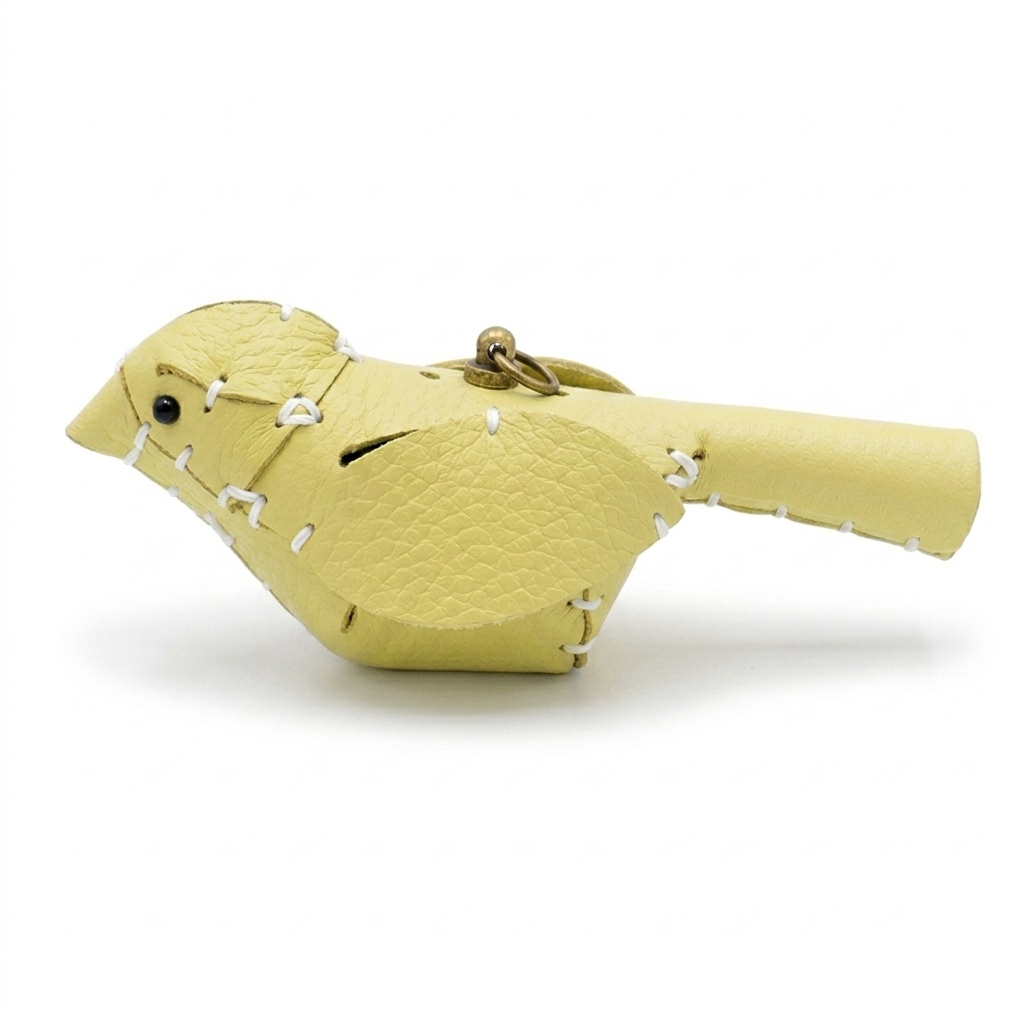 The Yellow colourway — a single leather bird, side view, pebble-grain panels whip-stitched with pale thread.